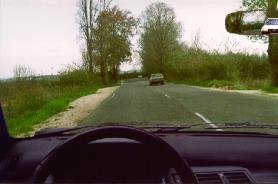 Two lane road divided by a dashed line, oncoming car