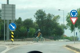 Cyclist entering a roundabout, give way and roundabout signs