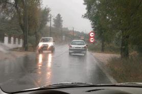 Rainy road with cars ahead and a no overtaking sign