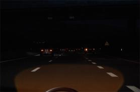 Night road with traffic ahead lit by the headlight beam
