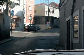 Narrow urban street corner with parked cars and poor visibility